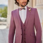 Homme en costume trois pièces rose mauve avec nœud papillon