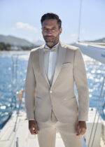 Homme en costume beige élégant avec nœud papillon sur voilier
