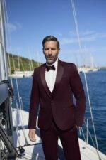 Homme en smoking bordeaux avec nœud papillon sur voilier