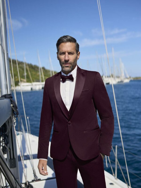 Homme en smoking bordeaux avec nœud papillon sur voilier