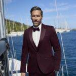 Homme en smoking bordeaux avec nœud papillon sur voilier