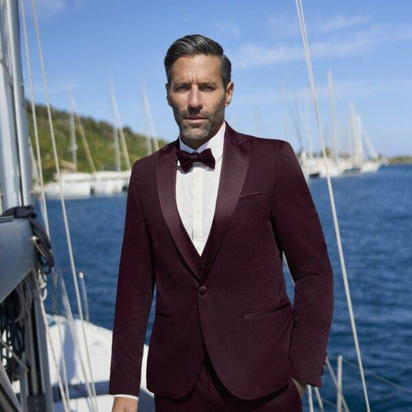Homme en smoking bordeaux avec nœud papillon sur voilier